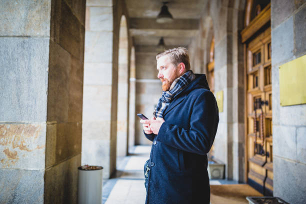 istock Young ginger businessman using mobile phone outdoors 921590998