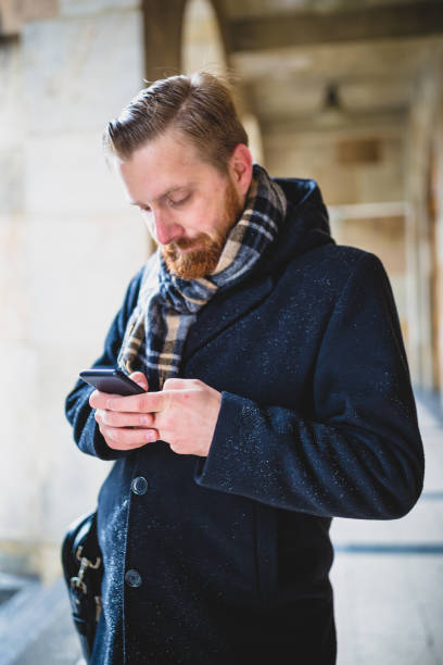 istock Young ginger businessman using mobile phone outdoors 921591002