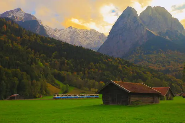 Train to Bavarian alps and wooden barns at sunset, Garmisch Partenkirchen, Bavaria - Germany