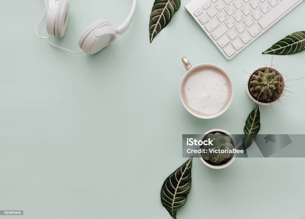 Neutral Minimalist Flat Lay Scene With coffee, keyboard, headphones and cactus Desk Stock Photo