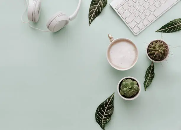 Photo of Neutral Minimalist Flat Lay Scene With coffee, keyboard, headphones and cactus