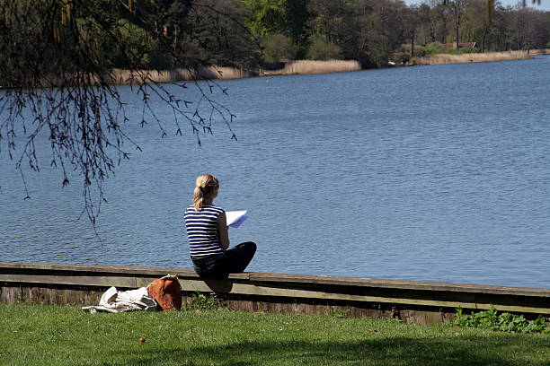 istock Female student reading by a lake in spring 92159366