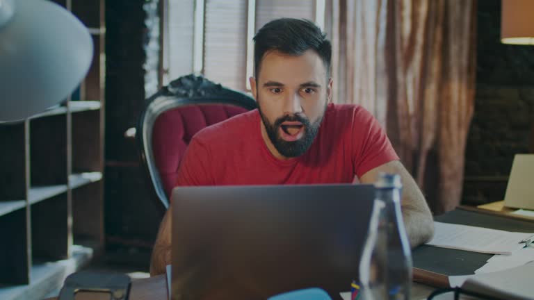 Happy business man reading good news on laptop computer in office. Yes sign