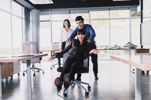istock Business people having fun pushing their partners racing on office chairs 921602092
