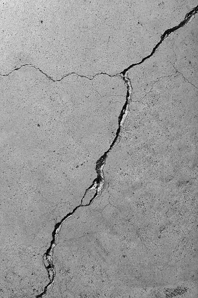 Closeup detail of a weathered cement floor with diagonal cracks.