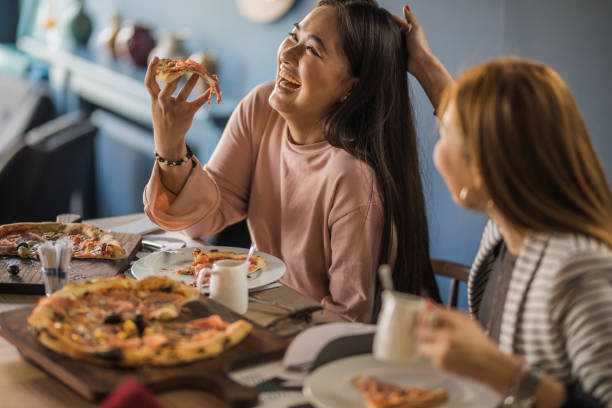 istock Cheerful Korean women having fun while eating pizza in a restaurant. 921618060