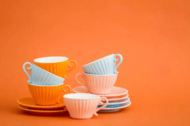 Cute colorful coffee cups on orange background with copy space