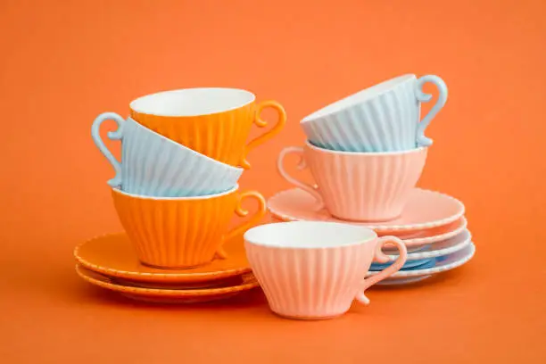 Cute colorful coffee cups on orange background with copy space