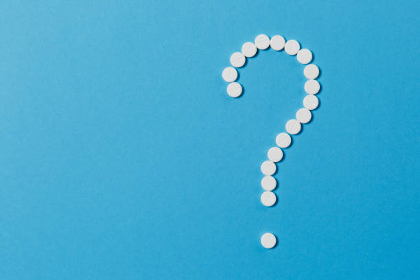istock Medication white round tablets arranged in question mark shape isolated on blue color background. Pills, sign. Concept of health, treatment, choice, healthy lifestyle. Copy space for advertisement. 921627014