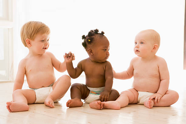 Three babies sitting indoors holding hands  group of babies stock pictures, royalty-free photos & images