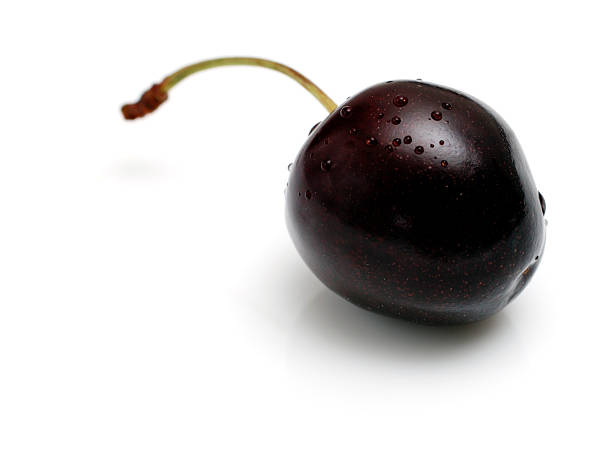 eine reife schwarze kirsche auf weißen teller mit leichten reflexion - black cherries stock-fotos und bilder