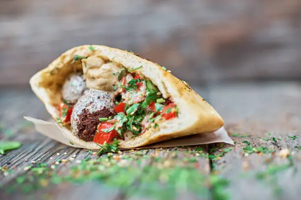 Falafel and fresh vegetables in pita bread on wooden table. Healthy lifestyle. Selective focus. copy space.