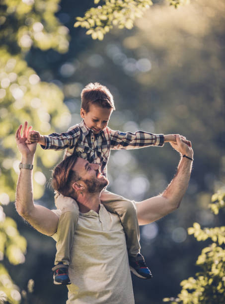 istock Young happy father carrying his son on shoulders during springtime. 921667220