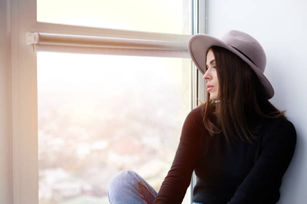 istock Beautiful boho woman in wool hat sitting by the window 921670478