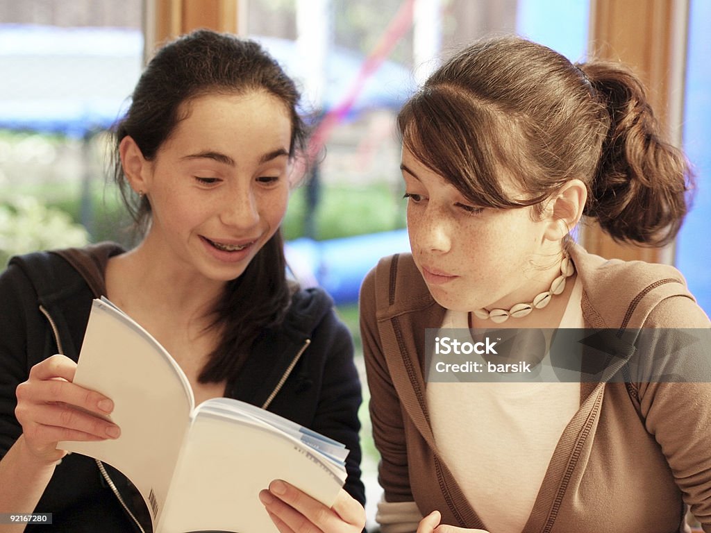 Ragazze adolescenti la lettura di un libro - Foto stock royalty-free di Abbigliamento casual