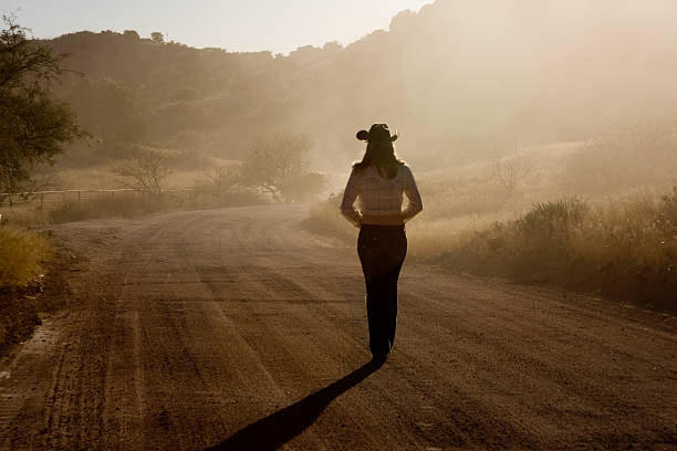 Cowgirl on a dusty road stock photo