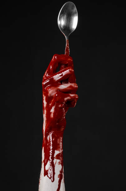 istock bloody hand holding a spoon, fork, halloween theme, bloody spoon, fork, black background, isolated 921674586