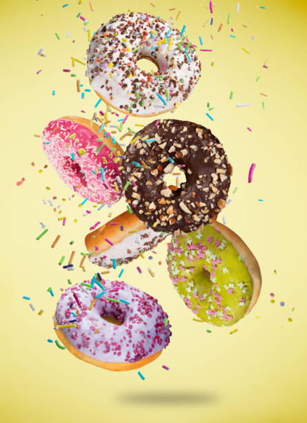 istock Tasty doughnuts in motion falling on pastel yellow background 921680366