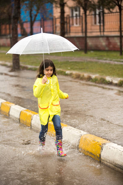 istock View of Girl Running Through Water Puddle 921680676