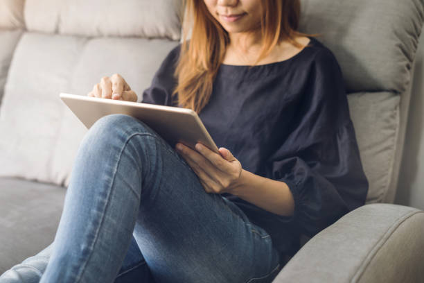 istock Young woman using tablet on sofa at home 921684422