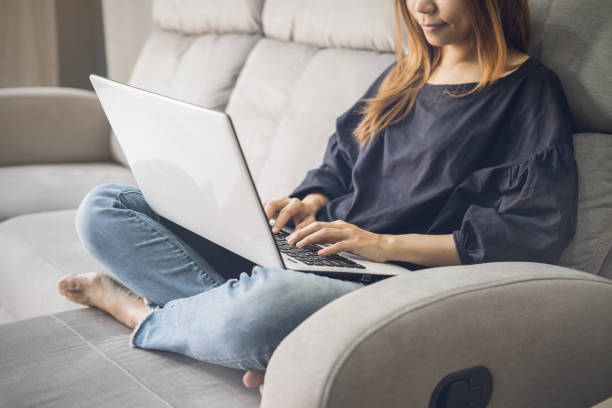 istock Young woman using laptop on sofa at home 921685248