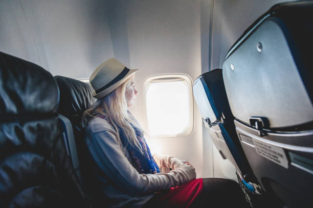 istock Young Woman Alone Looking Outside and Sitting inside Airplane 921685560