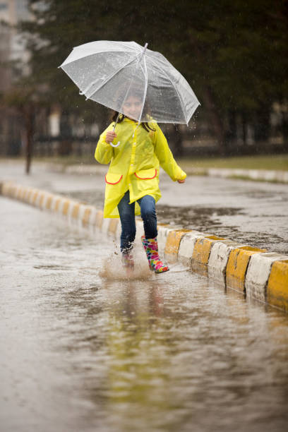 istock View of Girl Running Through Water Puddle 921696722