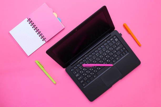 istock Laptop, notebook and pens on a pink background 921696928