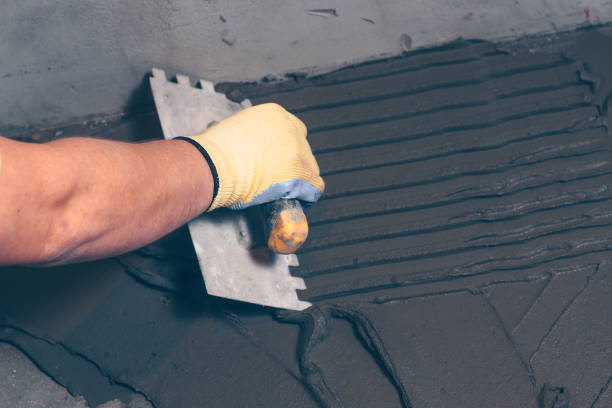 istock Working tiler applies glue on the floor with a notched trowel 921697000