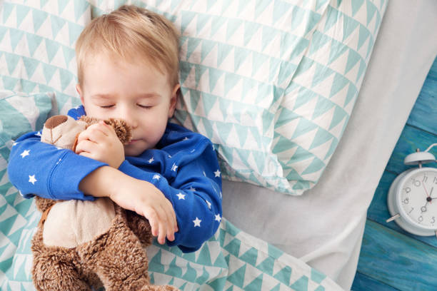 istock three years old child sleeping in bed with alarm clock 921697074