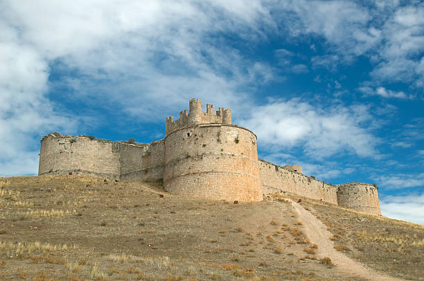Tourist woman exiting through an arched gate of the wall of the medieval city of Frias, Burgos