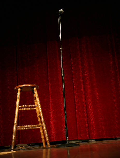 Mic stand and stool on comedy stage with red curtain stock photo
