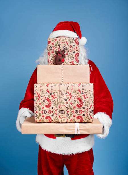 istock Santa Claus holding stack of christmas gifts 921699270