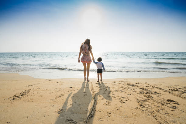 istock Mom walking on the beach with her son. 921699700