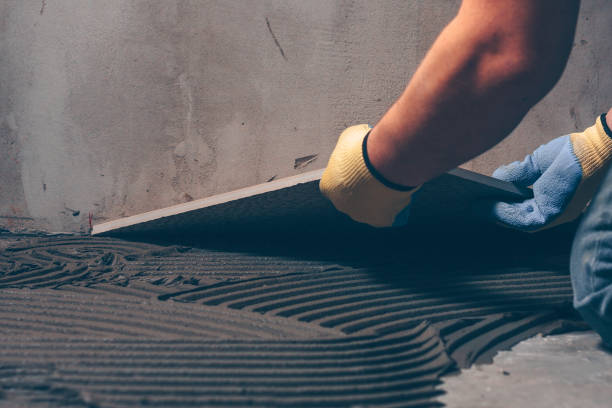 istock Working tiler puts on the floor a large square tile of ceramic granite 921700196