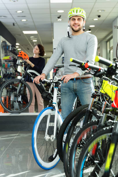 istock Man in helmet standing with sport bicycle in bicycle store 921700552