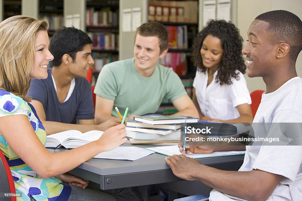 A group of college students studying at the library College students studying together in a library Group Of People Stock Photo