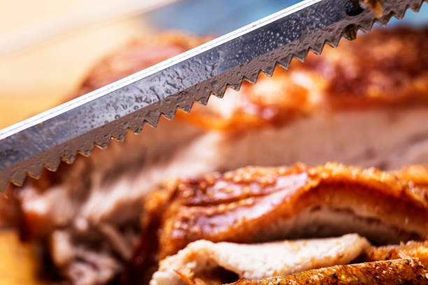 Close-up of perforated carving knife blade with roasted meat