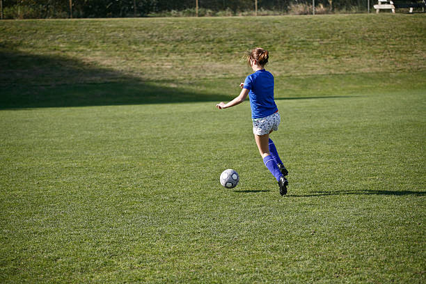 fille dribbler un ballon de football avant match - sports clothing kicking high up tall photos et images de collection