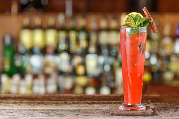 long drink fruit sling is on a bar counter on a blurry background of bottles with alcohol in a nightclub. - arm sling imagens e fotografias de stock