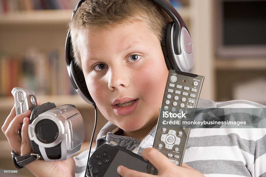 Młody chłopiec Trzymając wiele urządzeń elektronicznych - Zbiór zdjęć royalty-free (Brand Name Video Game)