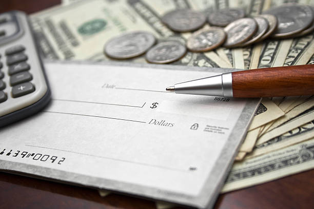 Close-up of blank check, US bills/coins, calculator and pen stock photo