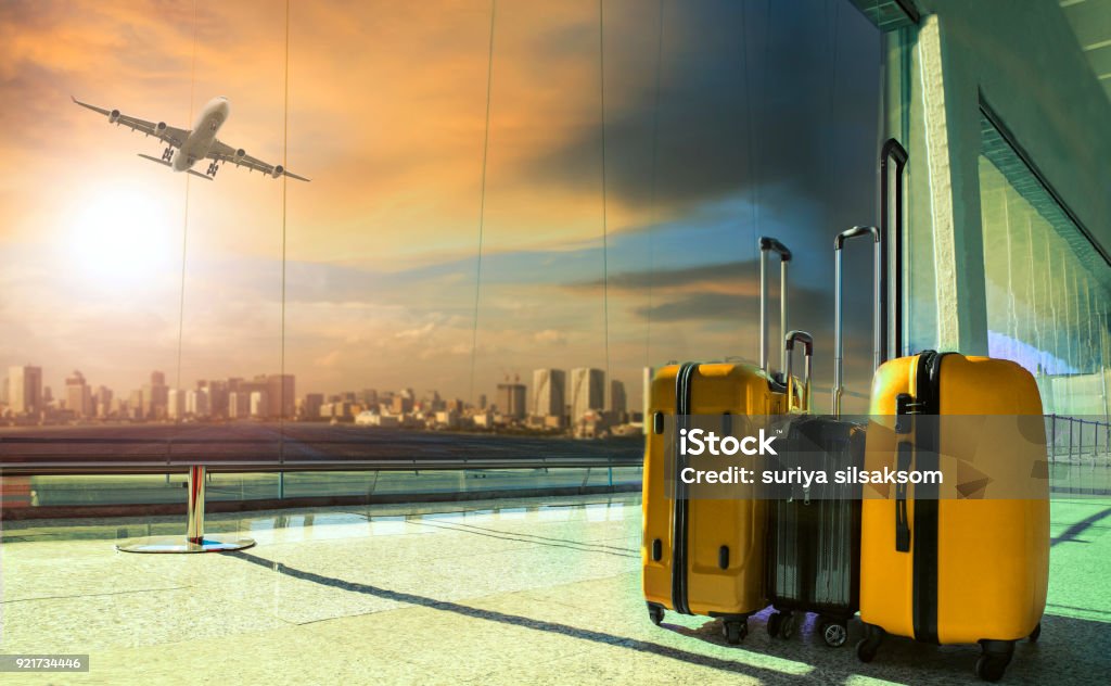 traveling luggage in airport terminal building with passenger plane flying over runway Airport Stock Photo
