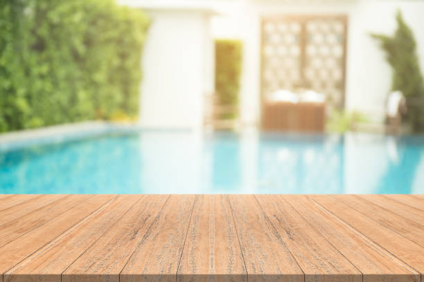 istock Empty wooden table in front with blurred background of swimming pool 921735818