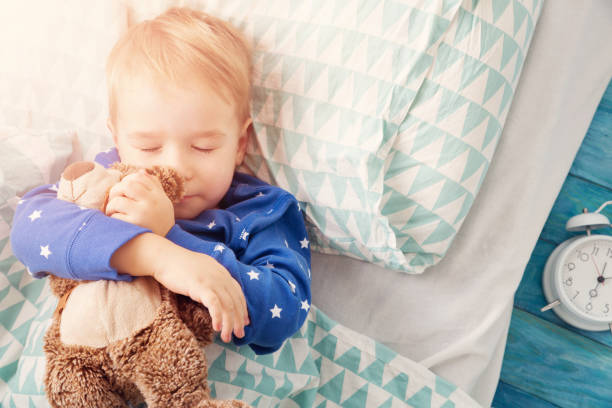 istock three years old child sleeping in bed with alarm clock 921736626