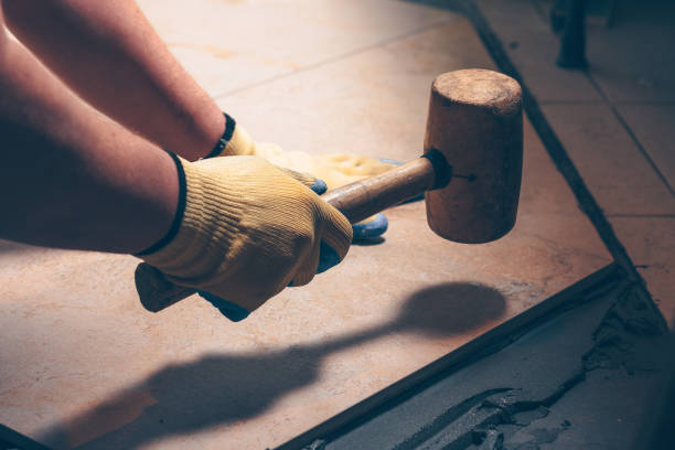 the working tiler knocks on the tile with a tile mallet, the professional checks the building level - rubber mallet imagens e fotografias de stock