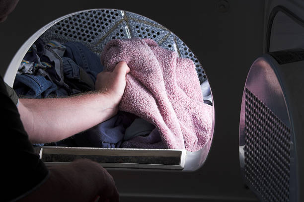 Doing Laundry A man taking laundry out of a clothes dryer. tumble dryer stock pictures, royalty-free photos & images