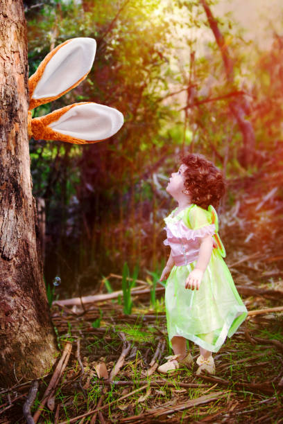 istock bunny ears behind a tree and little girl looking at it 921751506