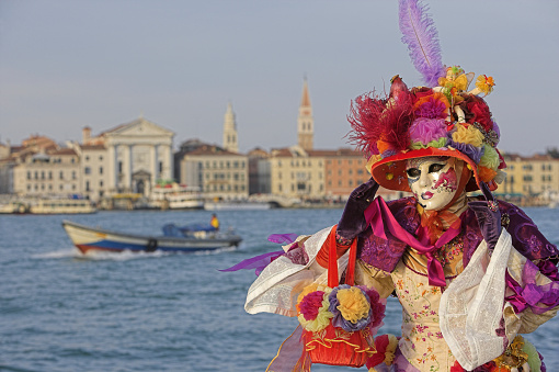  Venice, Italy- February 8, 2015. A couple disguised in Venetian costumes pose in front of Bridge of Sighs during the Venice Carnival days. Shot in St. Mark's Square. The Carnival of Venice is a annual festival held in Venice and is one of the most popular and appreciated carnival in the world.
