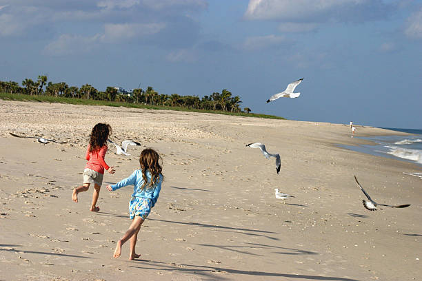 kids running on the beach stock photo